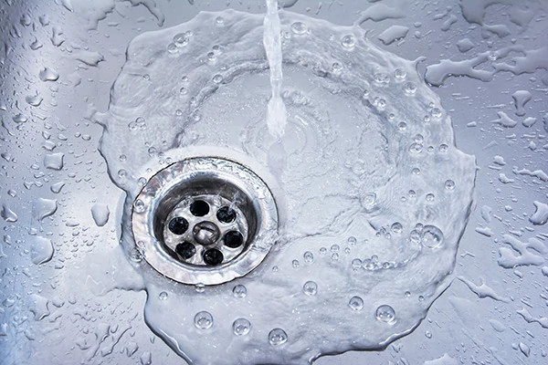  Close-up image of a sink drain with water running.