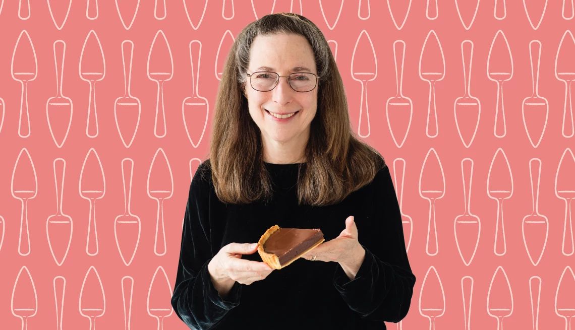 Rose Levy Beranbaum Releases Revised ‘The Cake Bible’ Rose Levy Beranbaum holding piece of chocolate pie against pink background with outlines of pie cutters on it