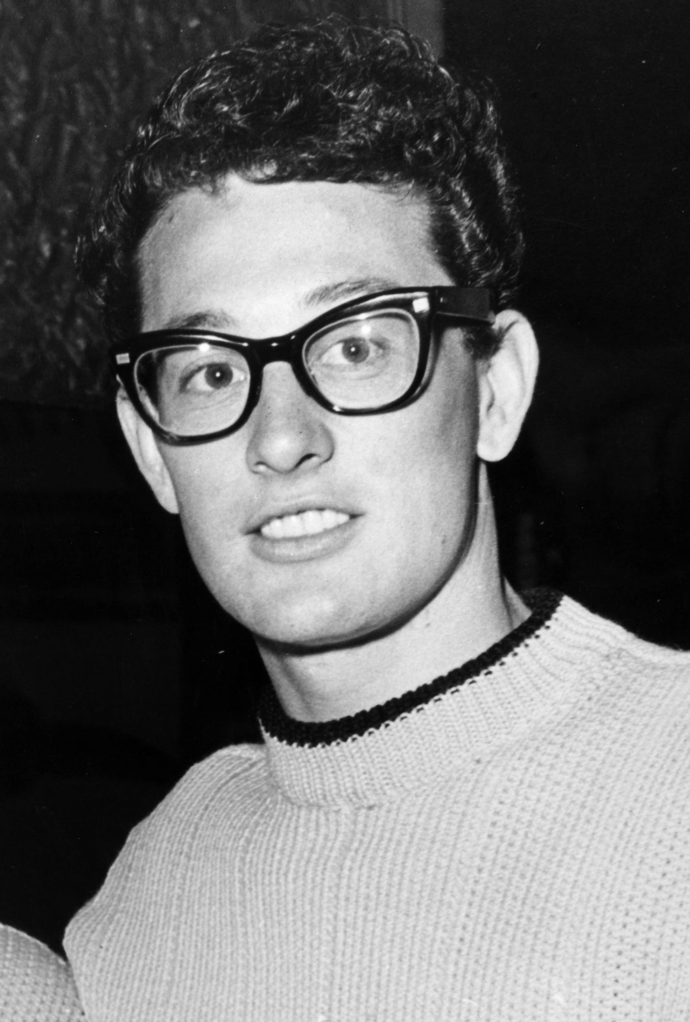 Buddy Holly buddy holly wears his signature thick glasses and light colored sweater