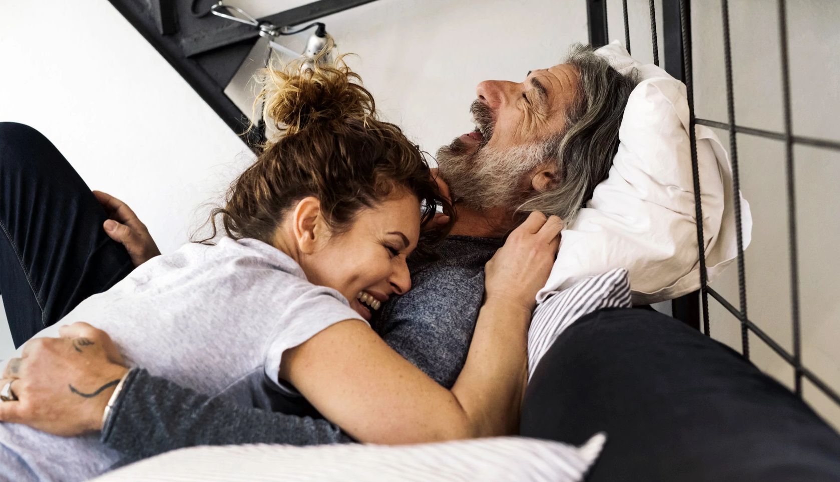 Health Benefits of Sex After 50 Happy couple relaxing at home on the bed.