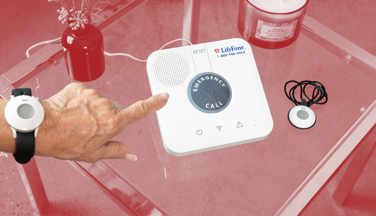 Woman wears a medical alert help button on her wrist and reaches out to push the help button on her LifeFone at-home device