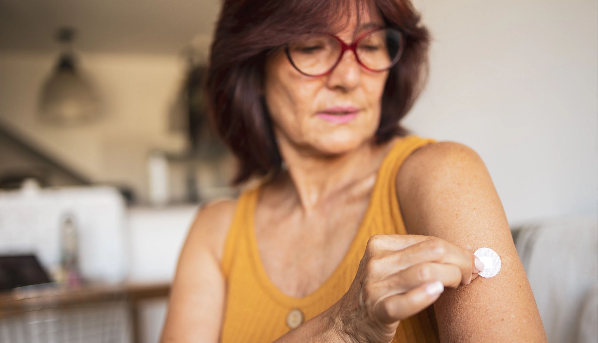 Menopausal hormone therapy may affect women's brain health A woman in menopause sticks a transdermal patch on the skin