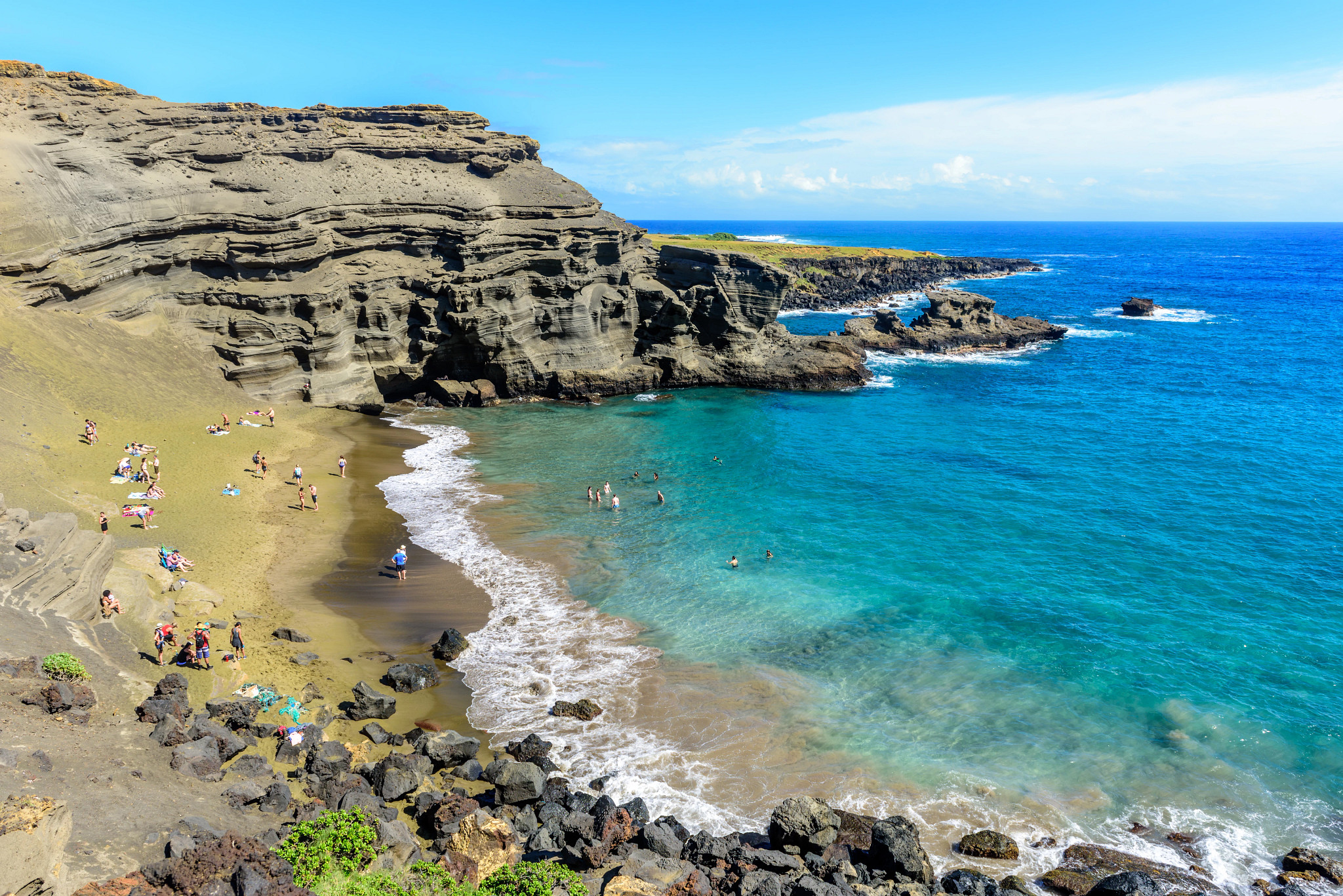 beachgoers in the sand and ocean at a beach in Hawaii