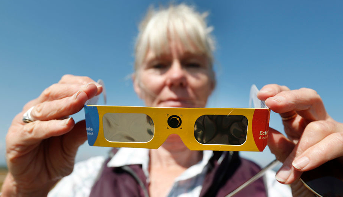 Una mujer sostiene unas gafas para ver el eclipse