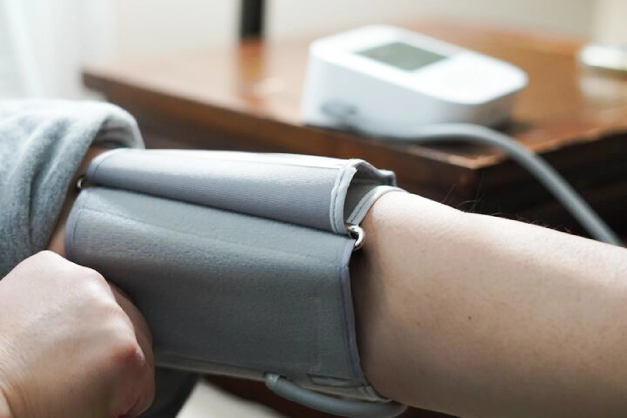 A man adjusting the cuff of the CONNEQT Pulse blood pressure monitor on his arm