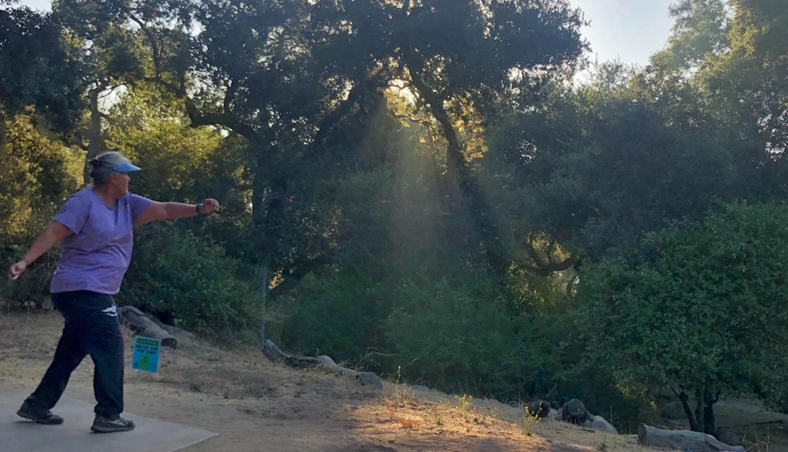 a woman throwing a disc at a disc golf course
