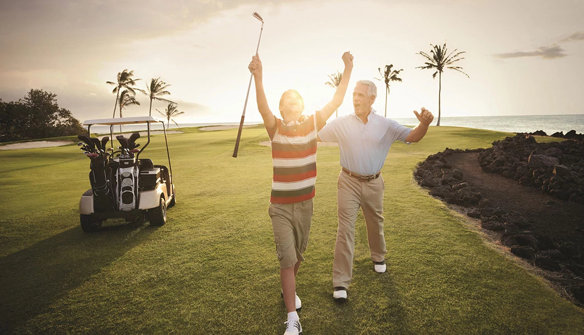 older man and younger boy with golf club in hand on golf course celebrating