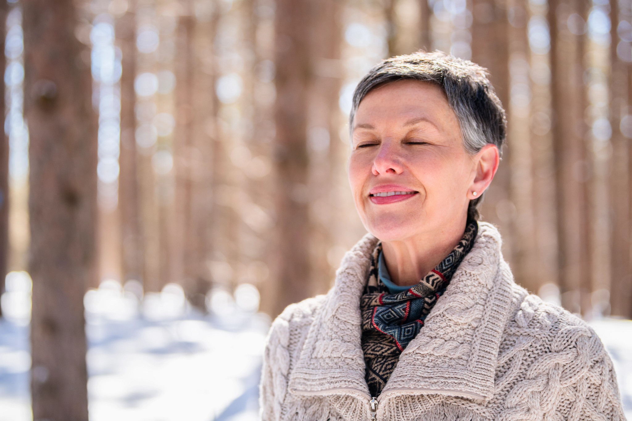 Woman in a snow covered woods looking zen with eyes closed