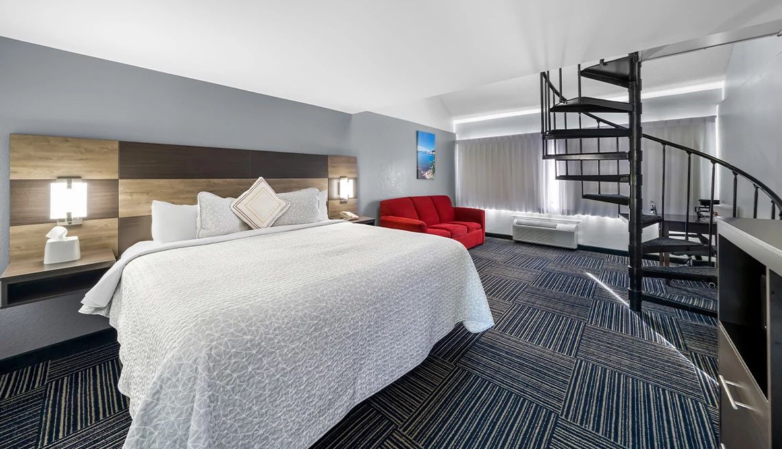 King-sized bed in a fancy hotel room with a spiral staircase