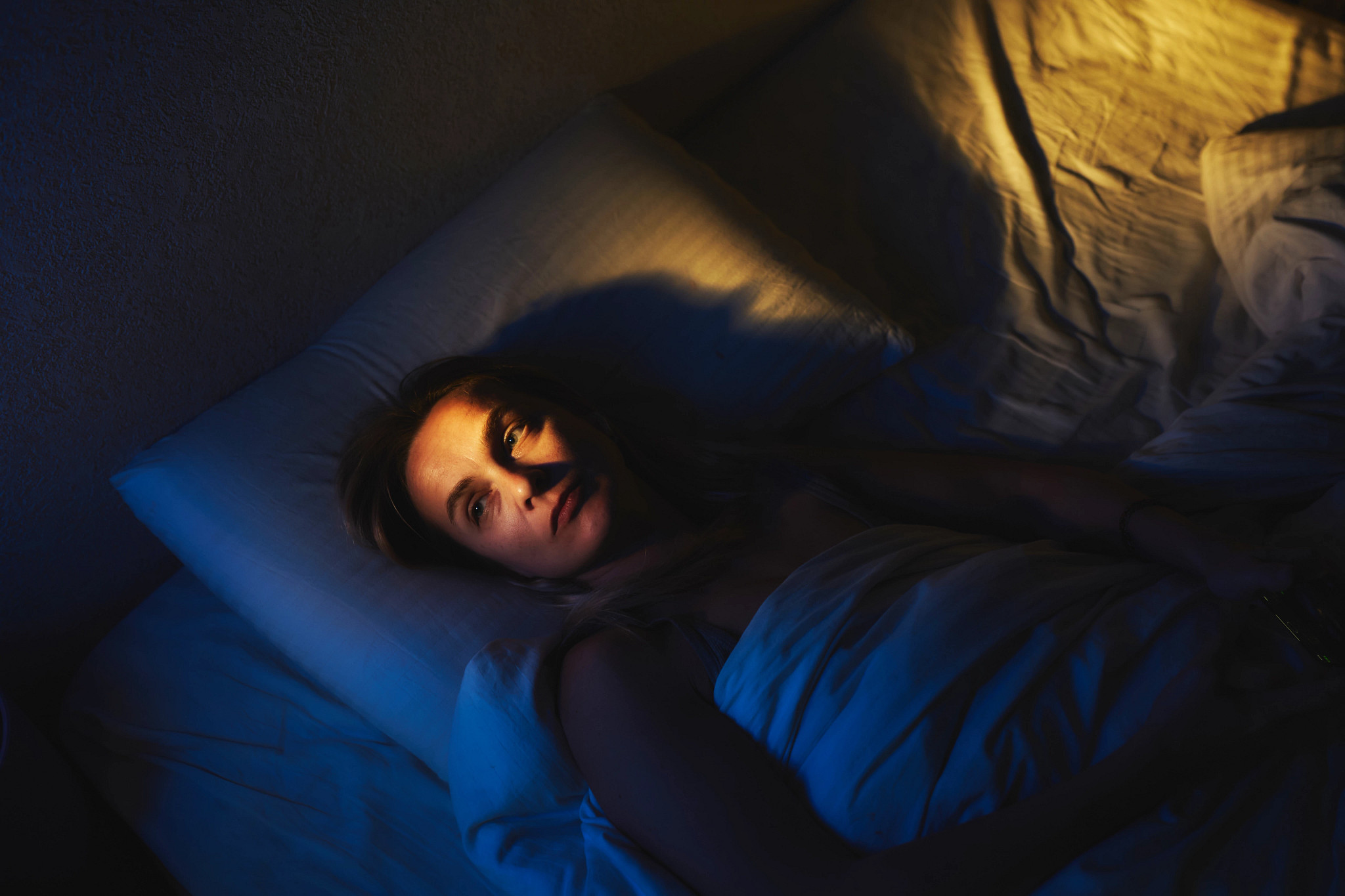 Mujer acostada en una cama con cara de desvelo.