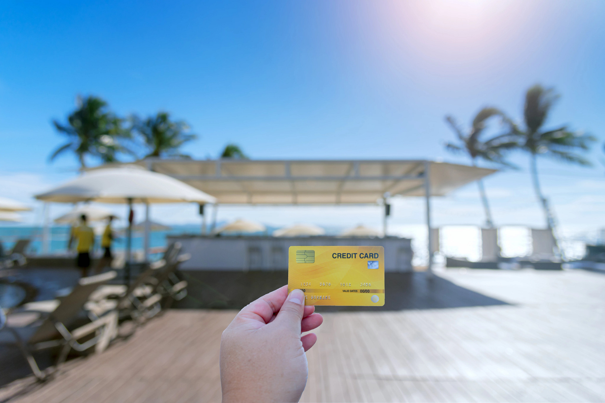 A hand holding a credit card at a beachside hotel