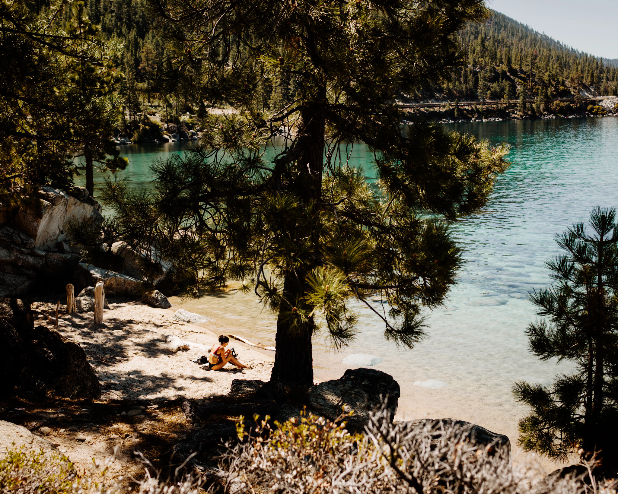 a woman sitting along a beach in Lake Tahoe