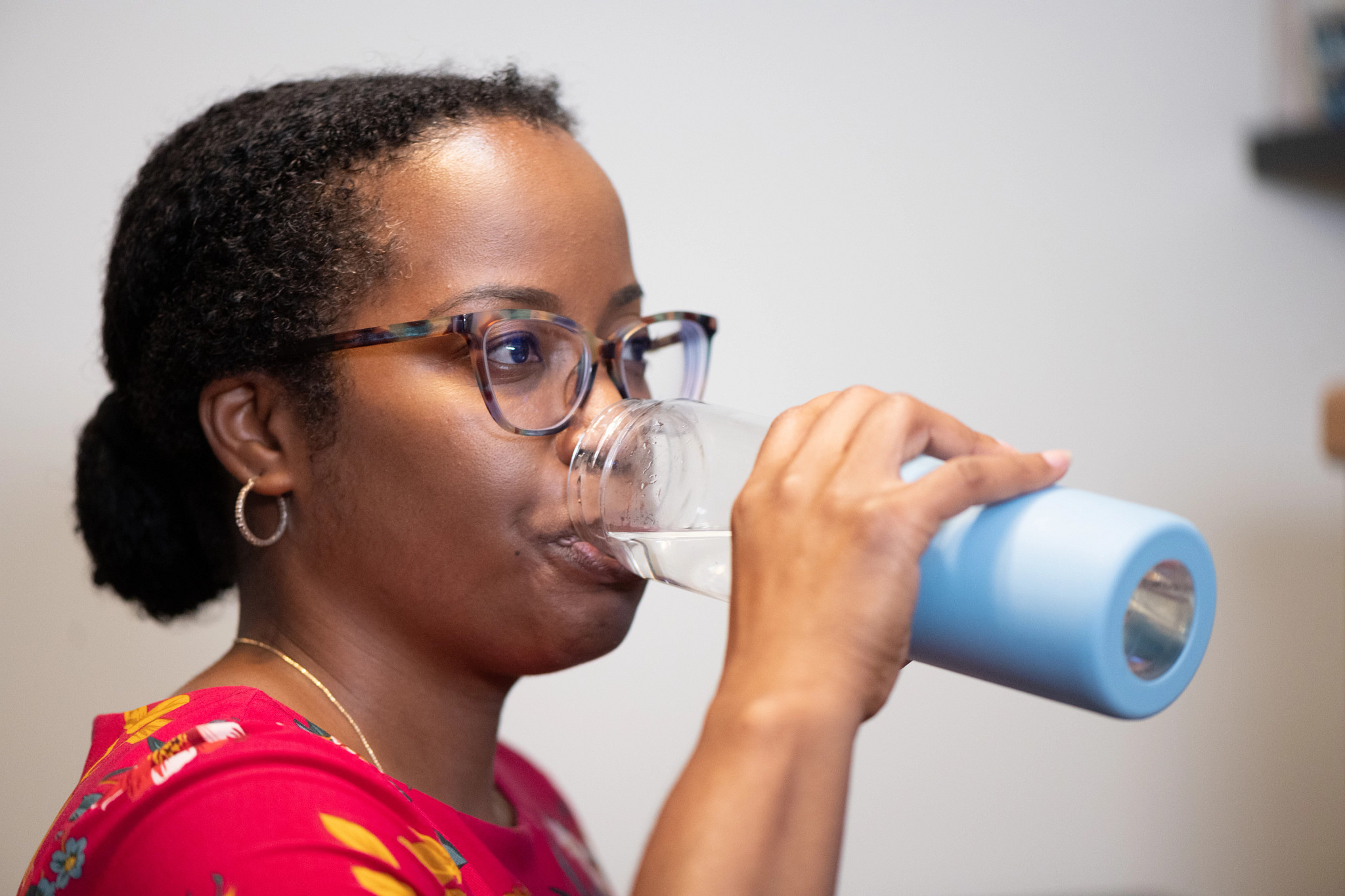 a person drinking water from a glass water bottle