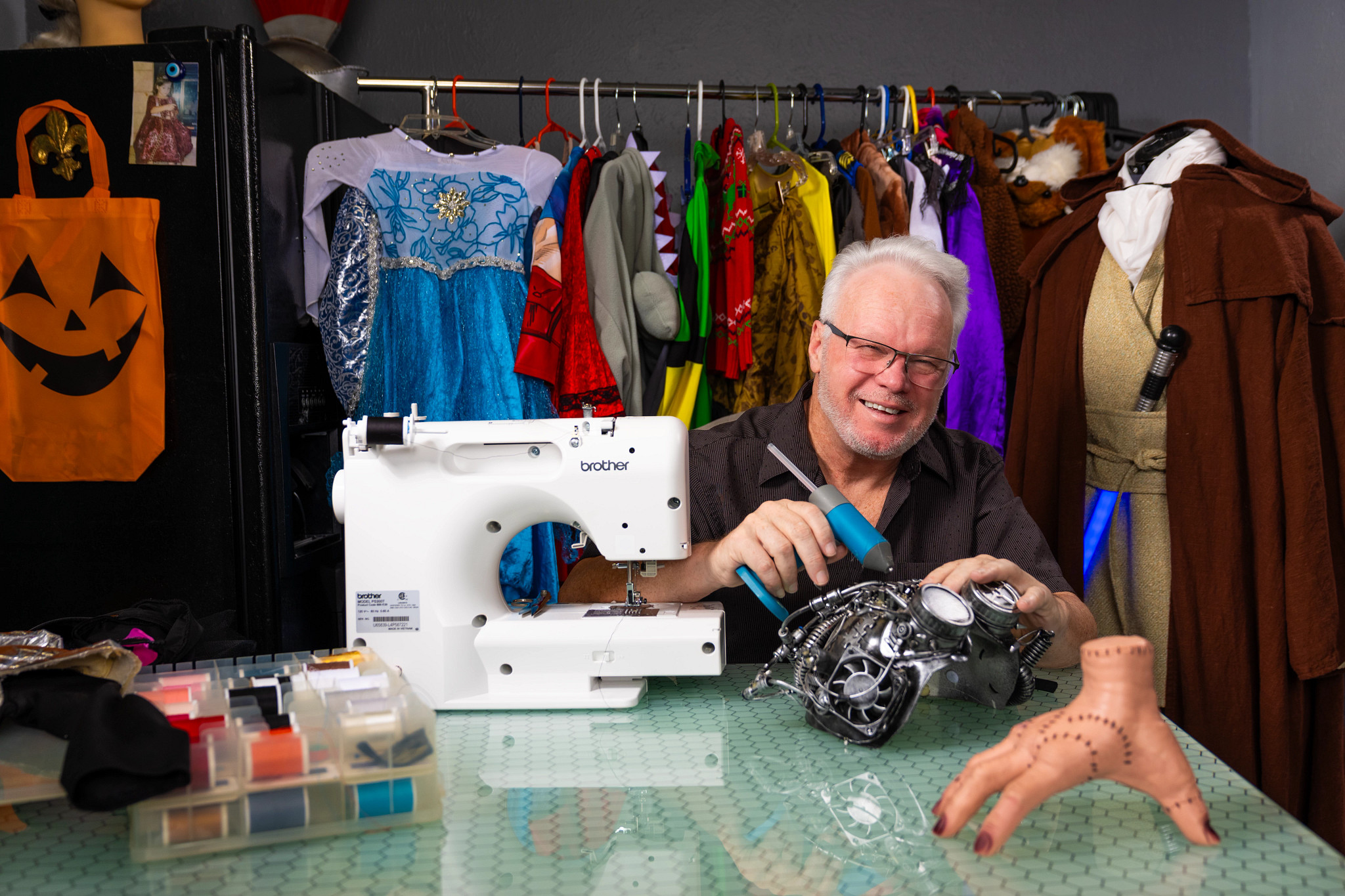 Christophe Waggoner is shown working on a Halloween costume with sewing machine and multi-colored thread spools