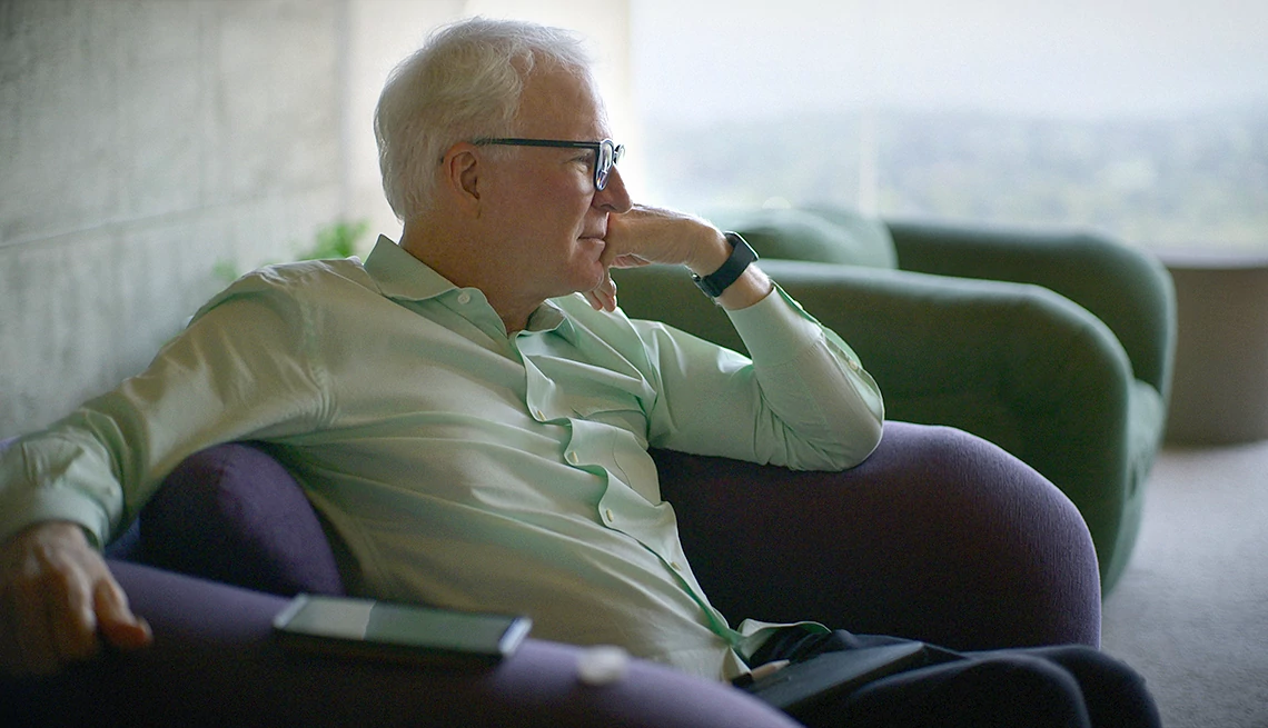 Steve Martin in the Apple TV Plus documentary STEVE! (martin) a documentary in 2 pieces Steve Martin sitting in a chair looking off into the distance in the Apple TV Plus documentary STEVE! (martin) a documentary in two pieces