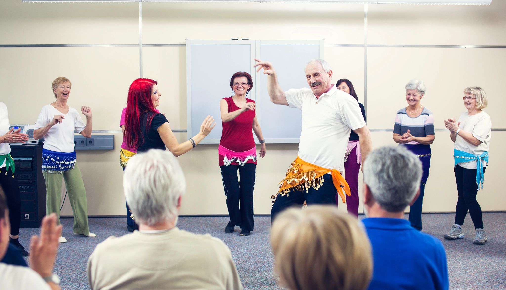 Audience having fun giving accompaniment by clapping to a senior man dancing with professional dancer a belly dance. Audience having fun giving accompaniment by clapping to a senior man dancing with professional dancer a belly dance.
