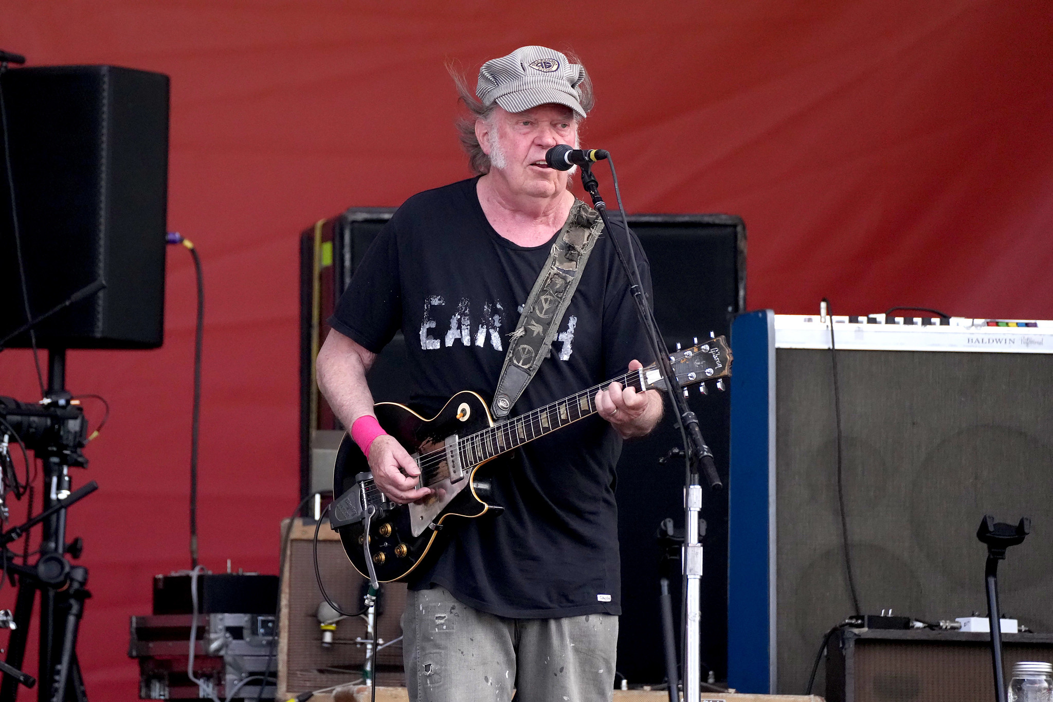 Neil Young playing an electric guitar onstage while singing into a microphone at the 2024 New Orleans Jazz and Heritage Festival