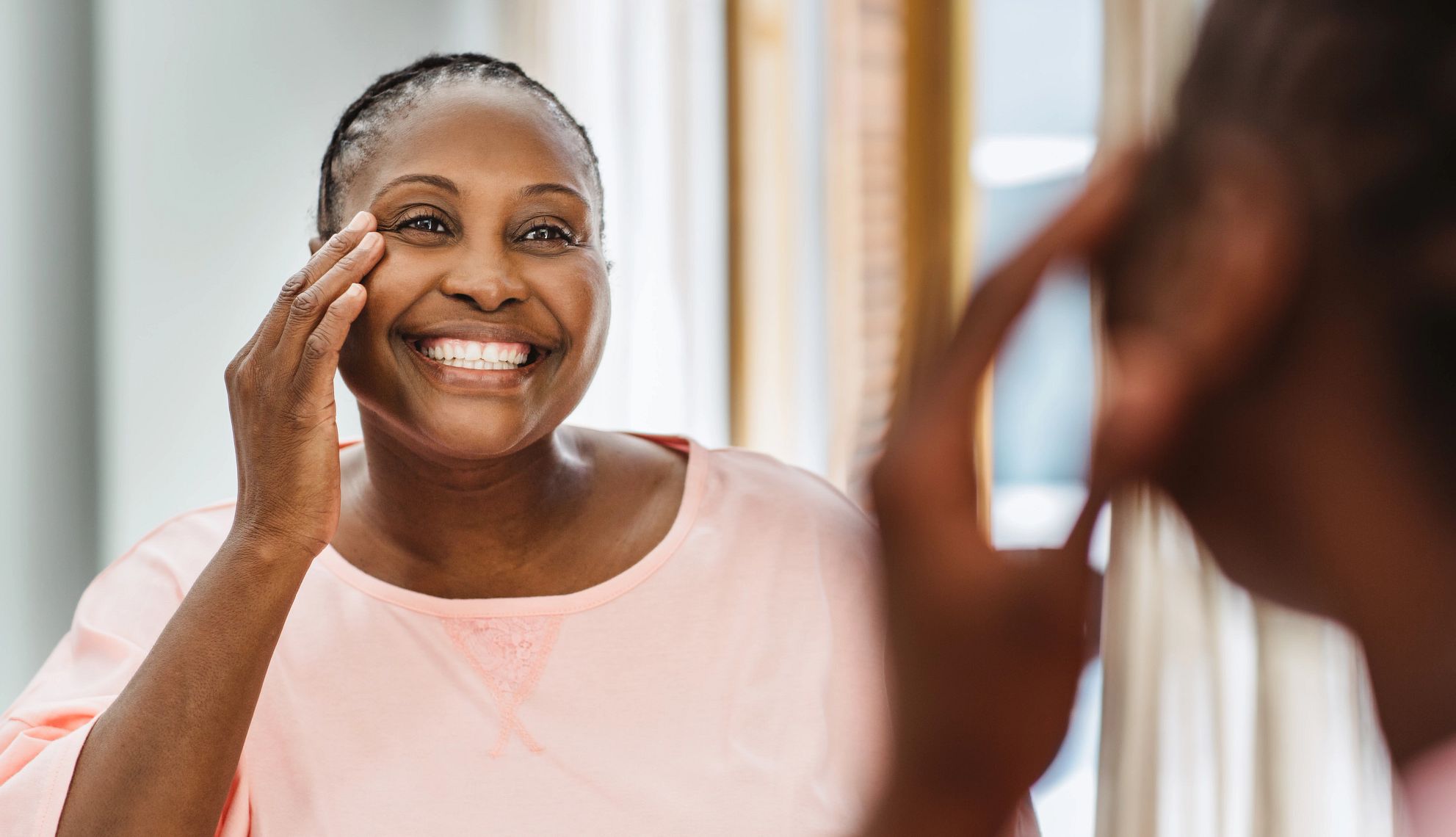 Los mejores productos de cuidado de la piel para piel negra fotos de una señora de piel negra sonriendo al espejo