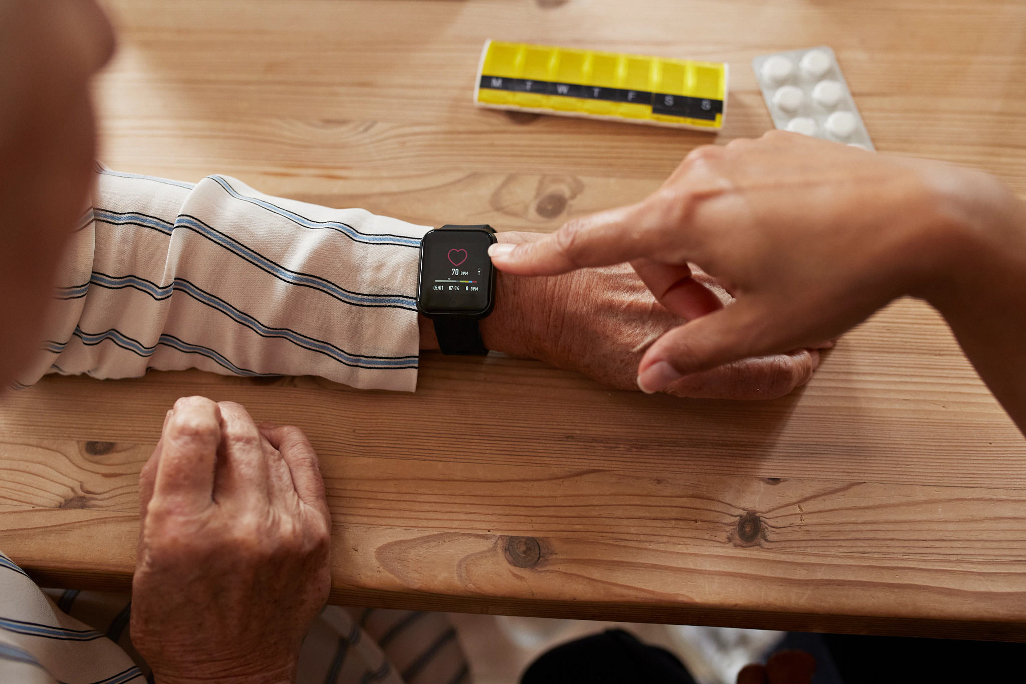 High angle view of female nurse checking heart rate of senior woman through smart watch