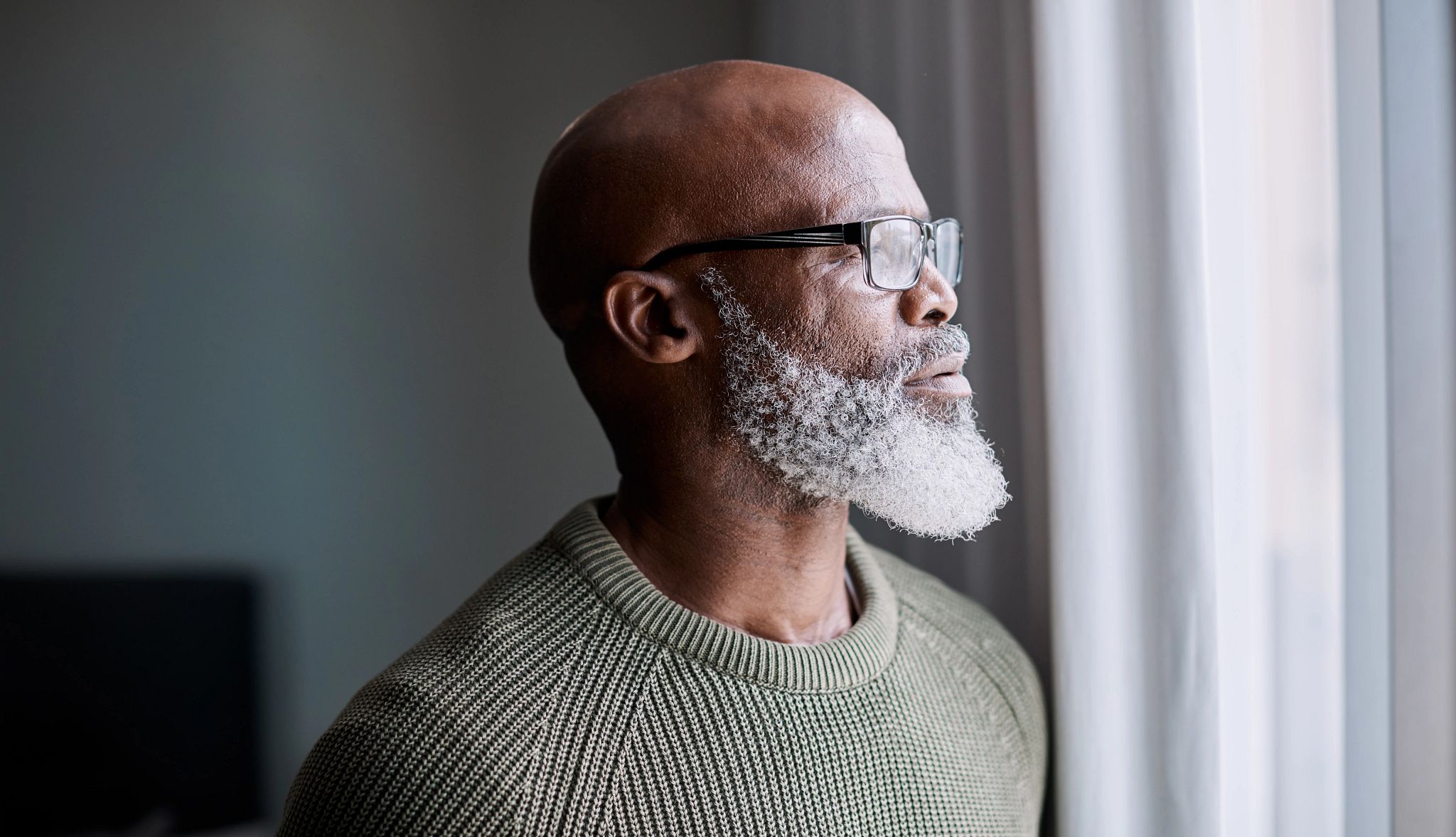 Shot of a mature man looking thoughtfully through a window at home Shot of a mature man looking thoughtfully through a window at home