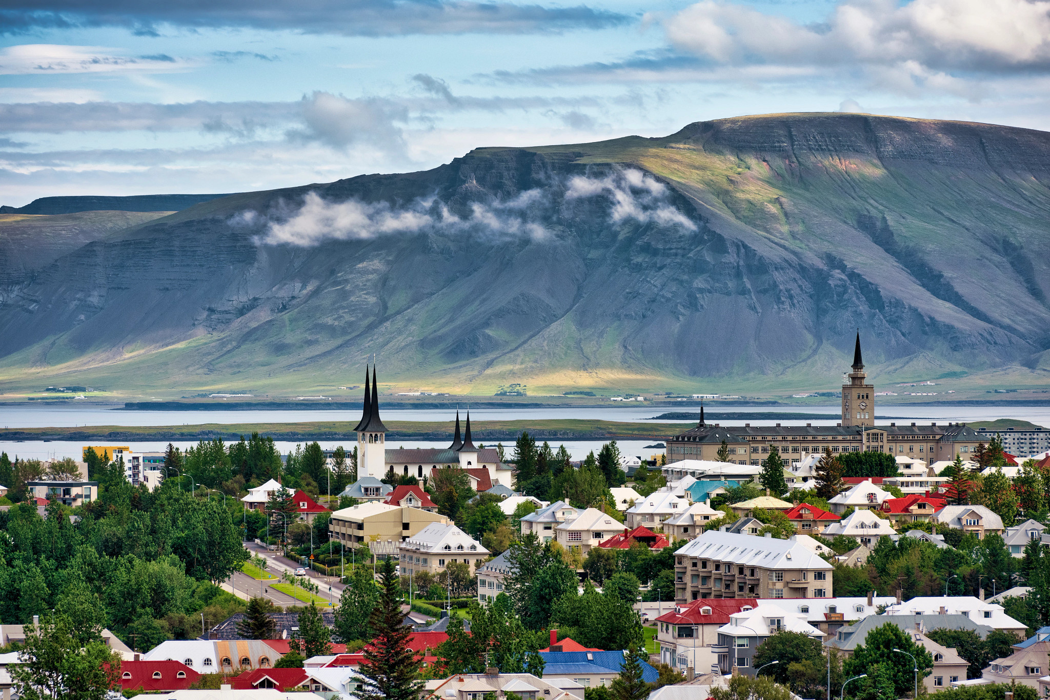buildings with a body of water and mountains in the background in Reykjavík, Iceland