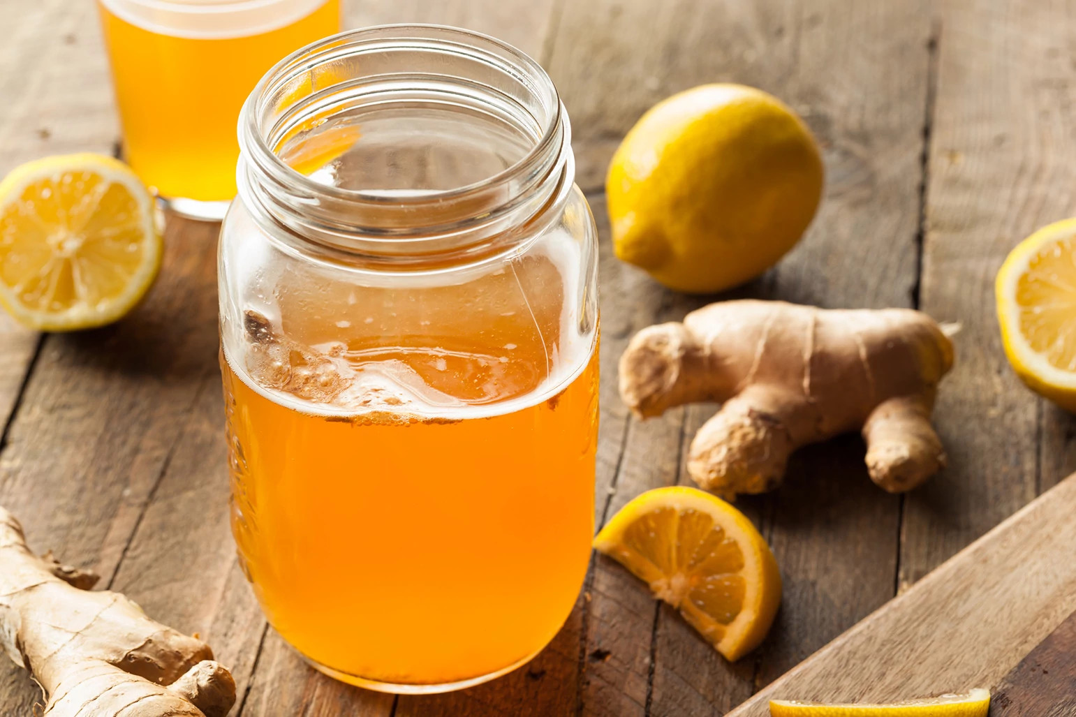 Kombucha in a mason jar surrounded by ginger lemon and oranges