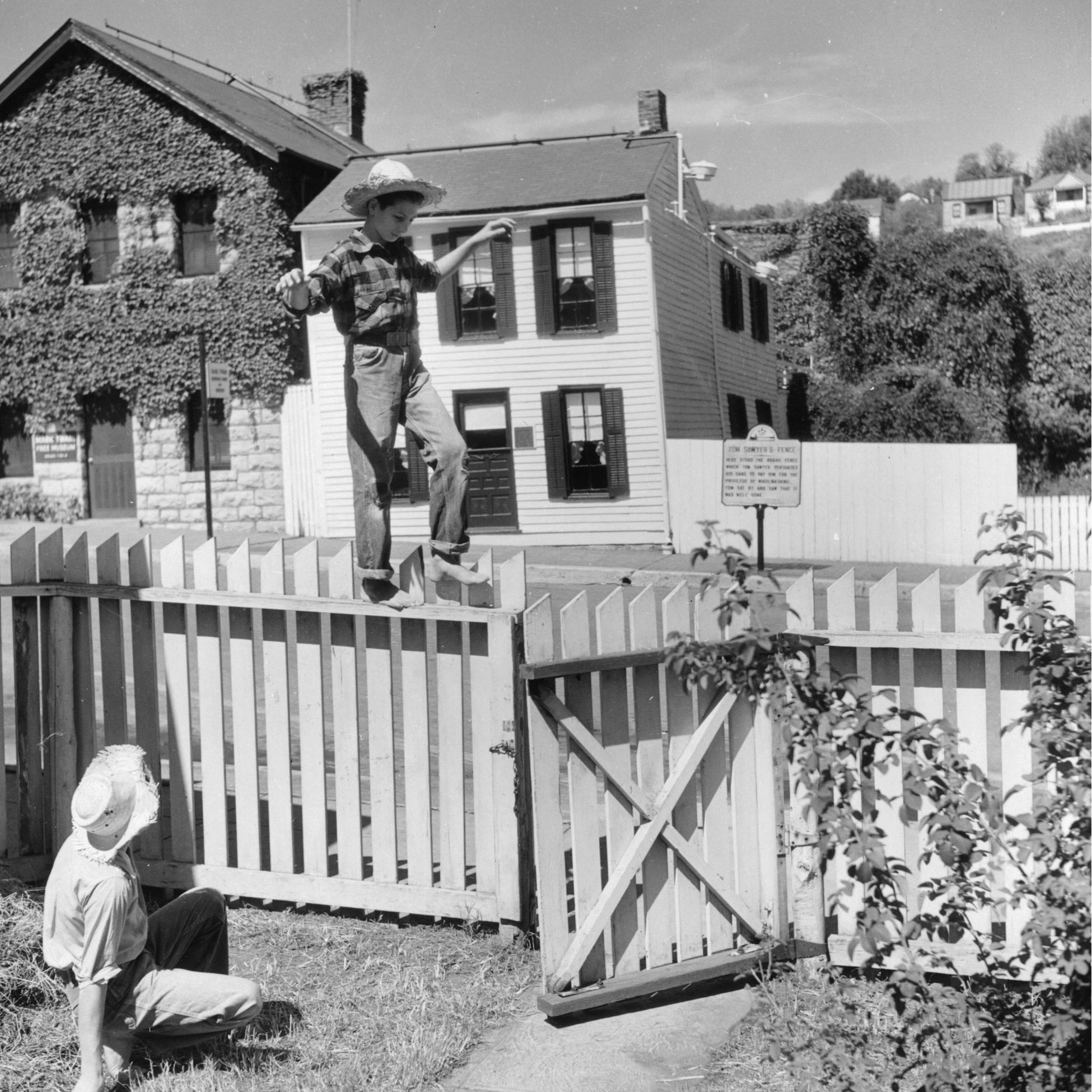 13 Fascinating Facts About Mark Twain two boys in straw hats playing around a white picket fence