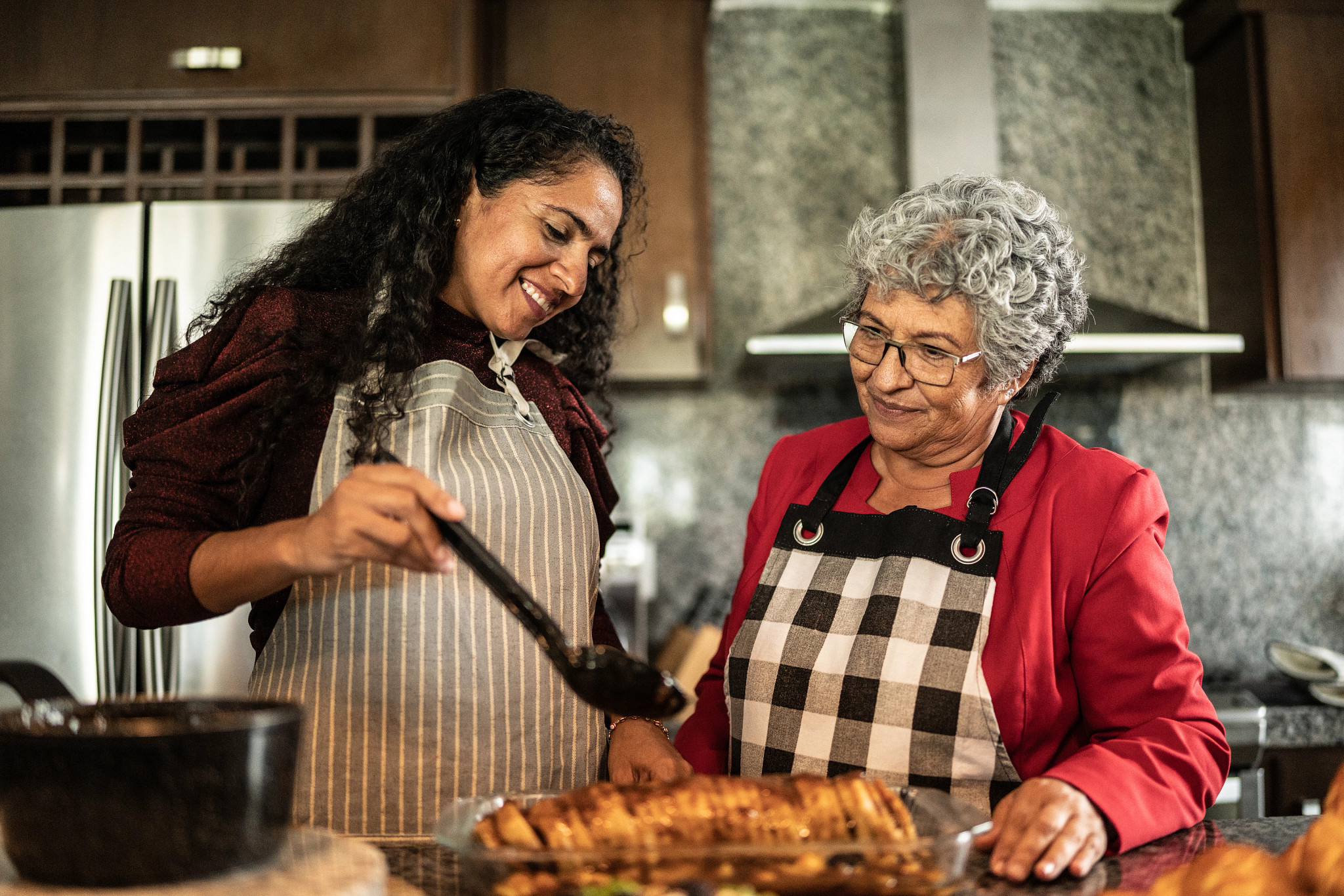 Mother and daughter preparing food at the kitchen counter at home