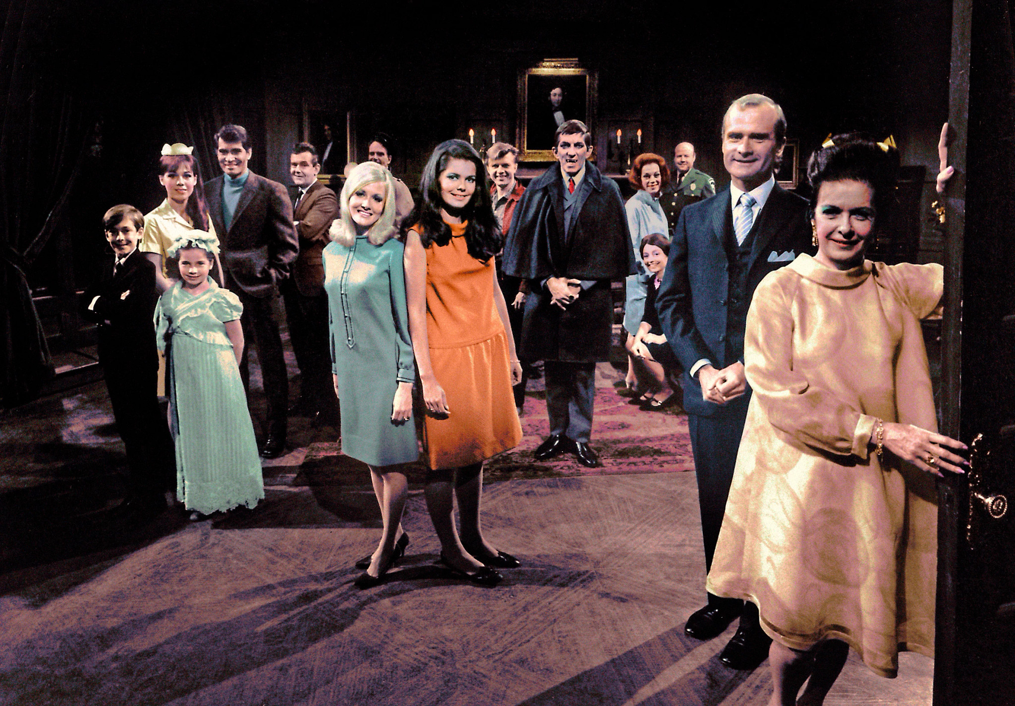 Large group portrait of Dark Shadows cast posed in a dark, vintage interior with dramatic lighting