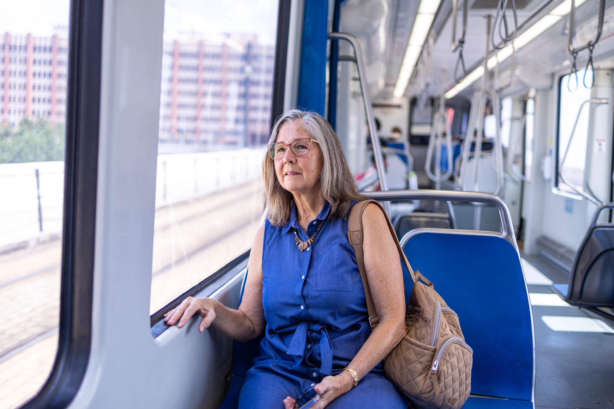a photo shows an older adult woman riding public transportation