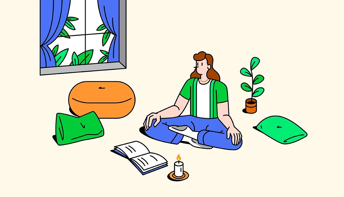 Home sanctuary A woman sits on her floor in the lotus position. There is a candle, a book and pillows on the floor around her. The drapes are open with a leafy view outside.