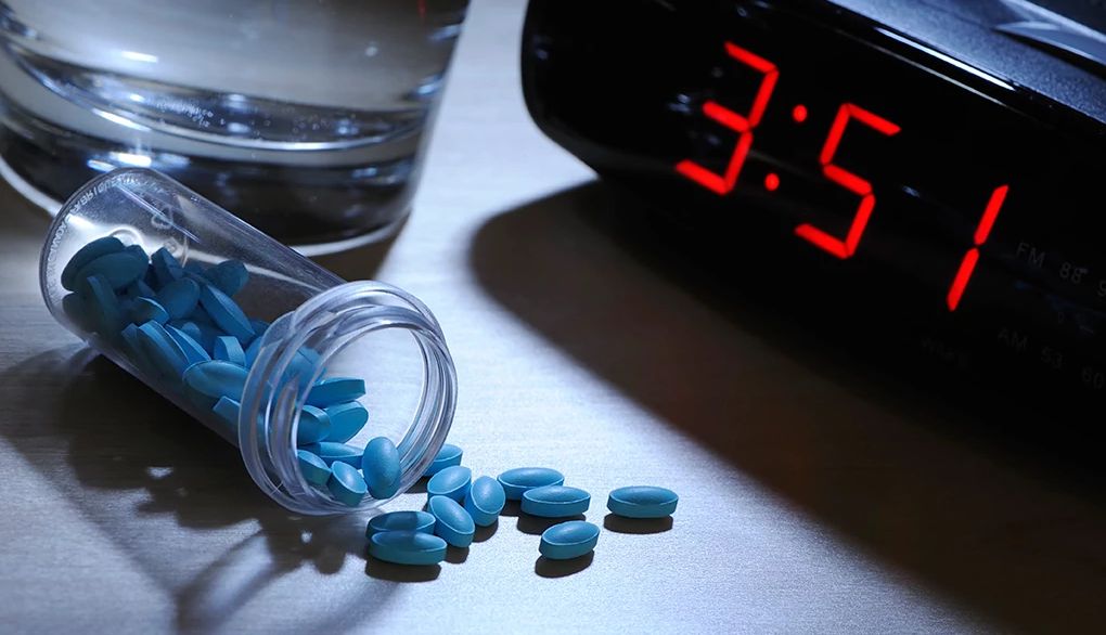 Sleeping pills have been linked to serious health risks An up-close view of an alarm clock, pills and glass of water