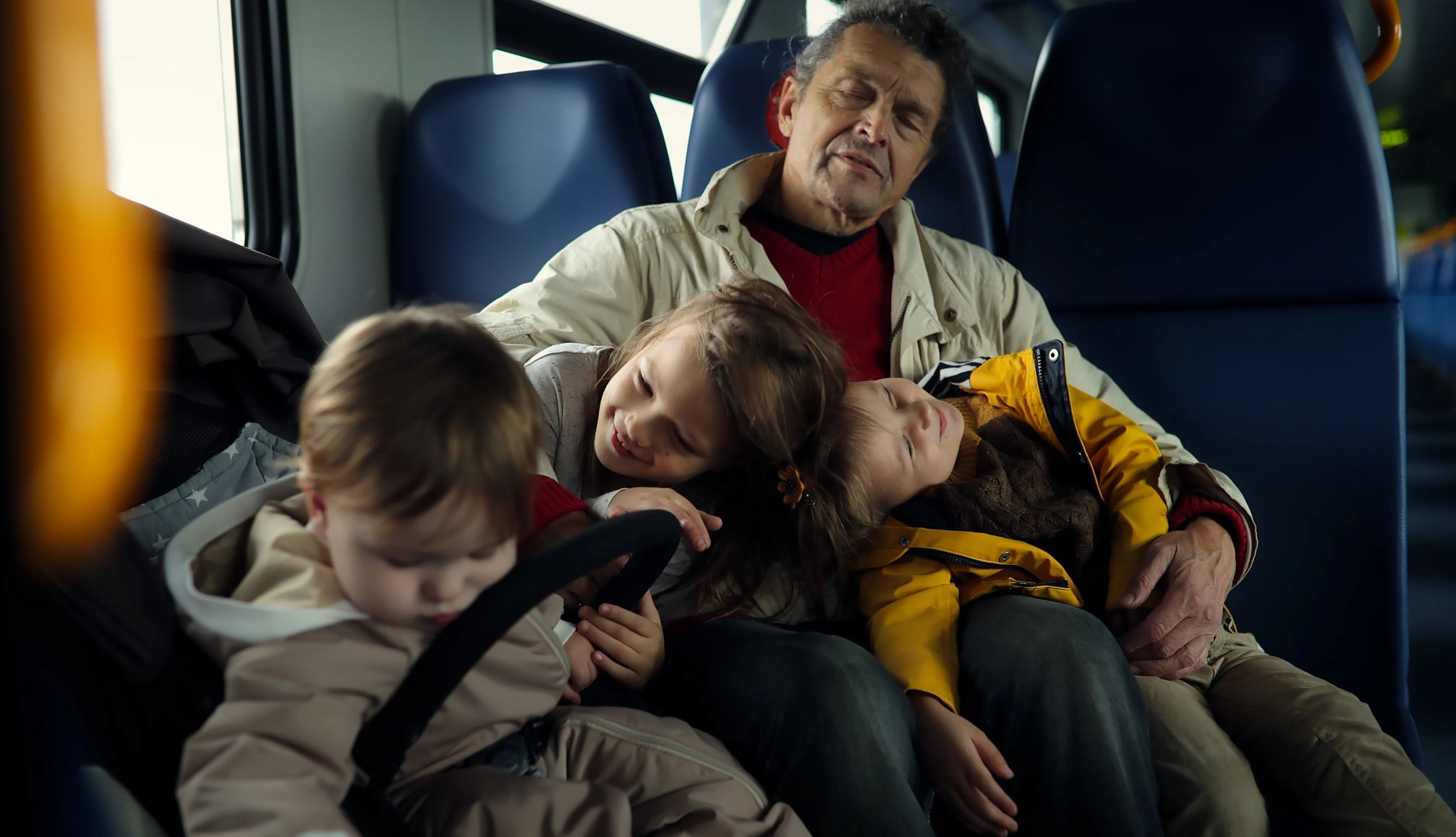 starting a day too early can lead to a bad day for the whole family a grandfather holds a two sleeping children, with another in a sleeping in a car seat