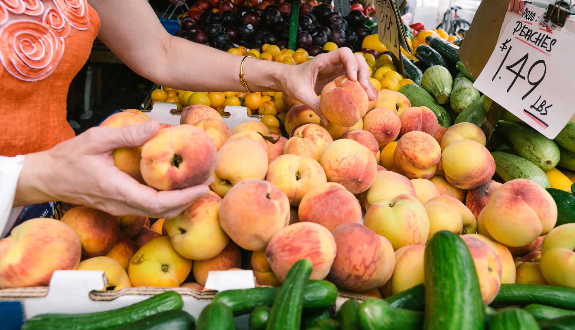 Fruits and Vegetables Hands picking up peaches from a pile