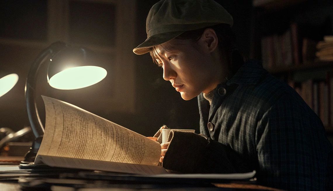 Zine Tseng reading a book at a desk in the Netflix series 3 Body Problem