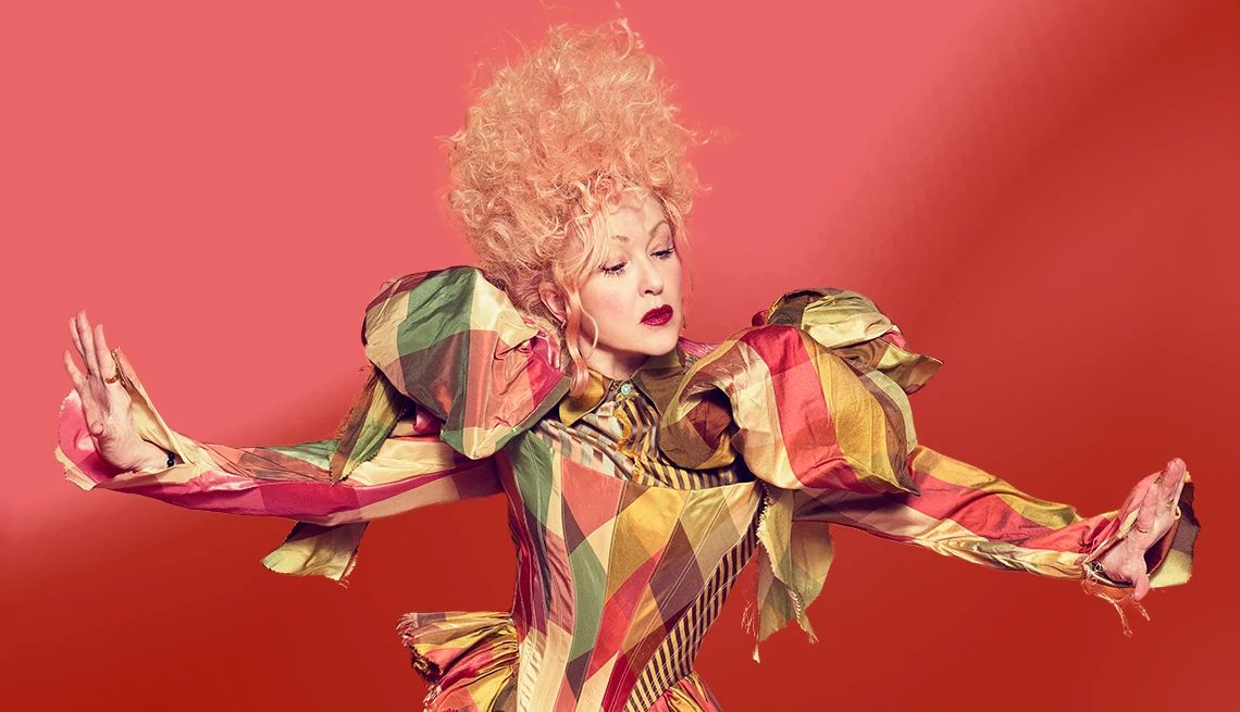 Cyndi Lauper Is Still Having Fun cyndi lauper modeling a unique outfit and hairstyle in front of a red background