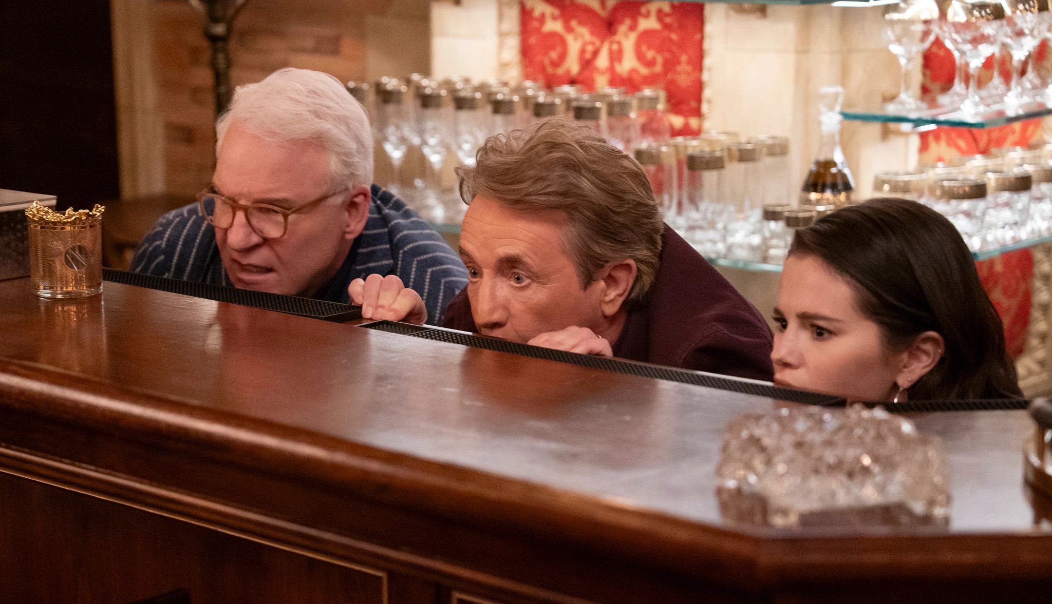 Best Things Coming to Hulu stever martin, martin short and selena gomez peer over a bar in a scene from only murders in the building