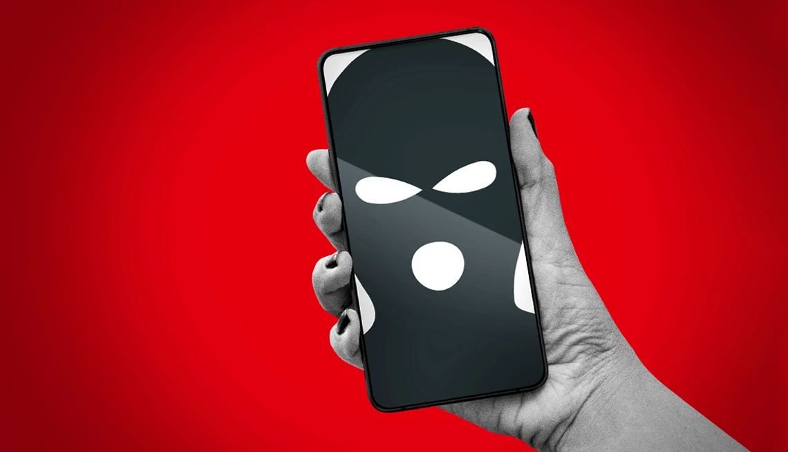 a hand holding a phone with a masked criminal on the screen