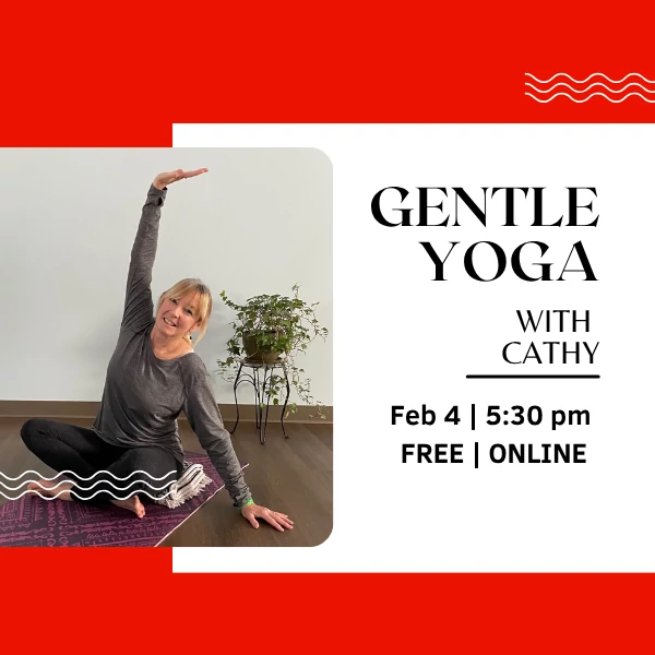 A woman sitting on a yoga mat in a living room, smiling and stretching her arms upward.
