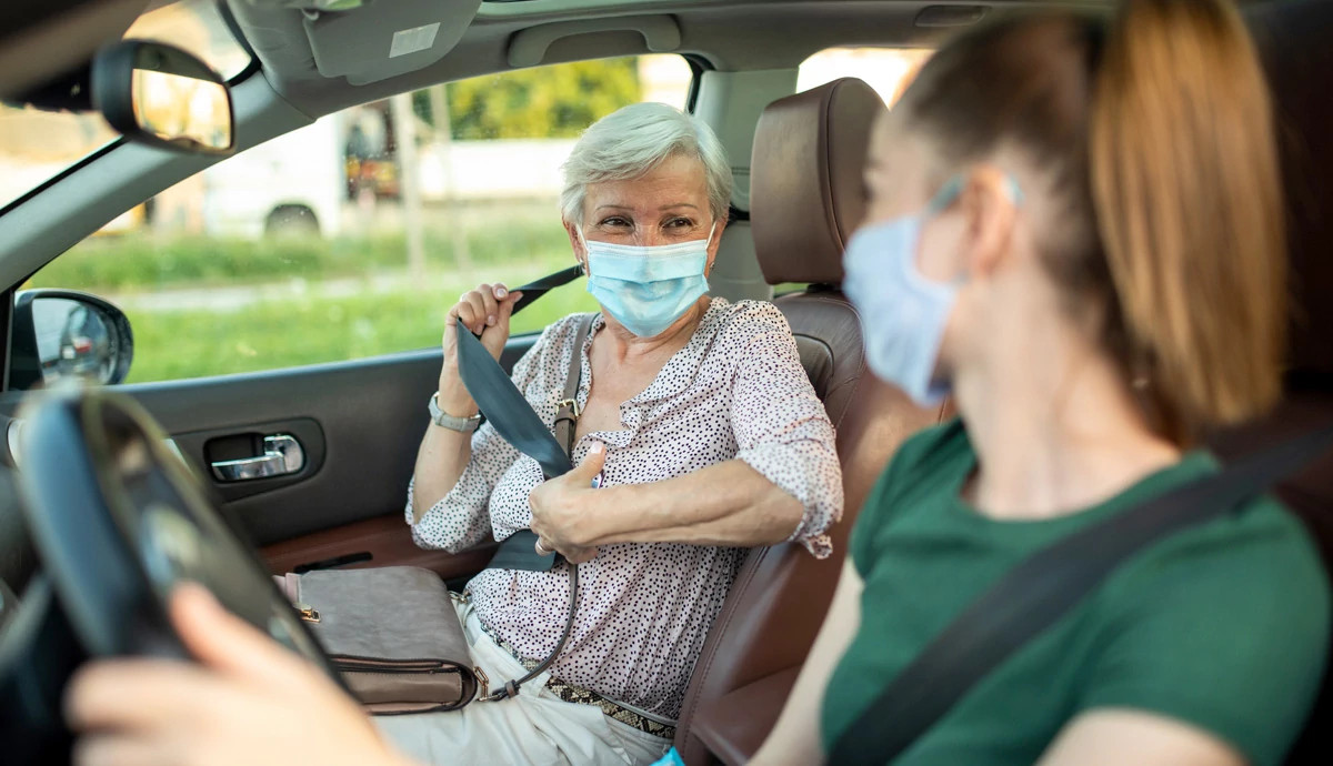 Woman wearing mask in car with driver.