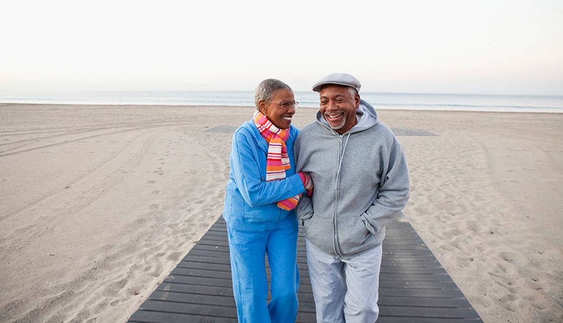 Walking can be a great exercise for your memory A man and woman smiling and walking together on the beach