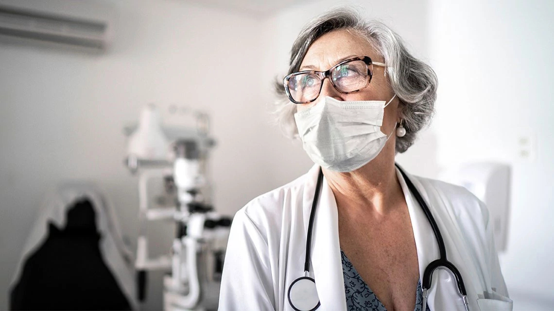 female eye doctor, mask, in doctor office, wearing white coat