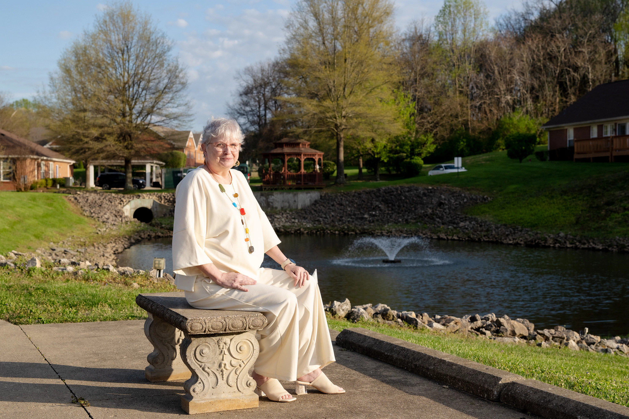 a woman sitting on a bench next to a pond