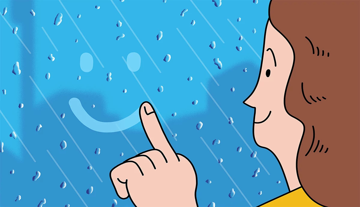 A gif shows a woman drawing a smiley face onto a rain-drenched window with her finger