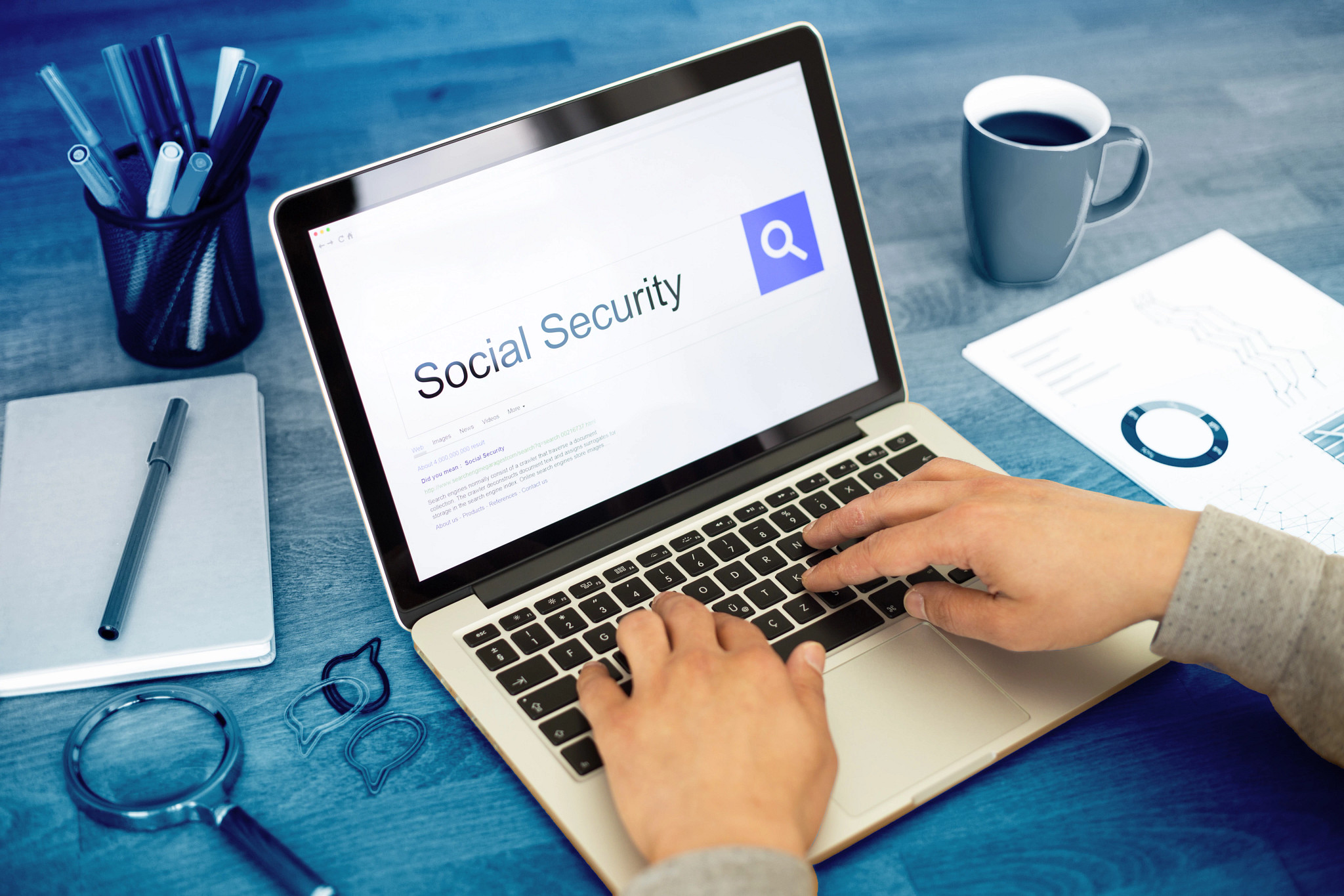 Hands type on a laptop. On the screen is a search for Social Security.