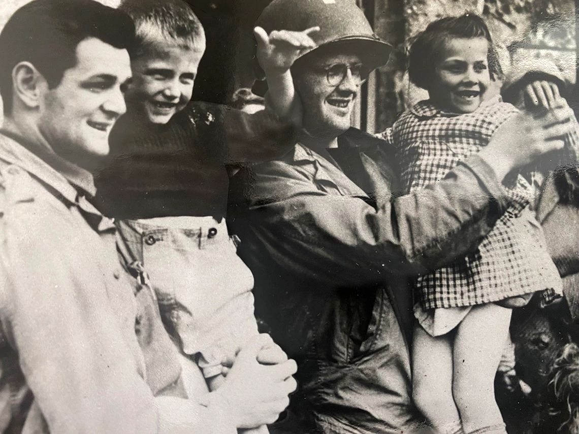 dos soldados americanos sostienen cada uno a un niño en sus brazos en una imagen en blanco y negro