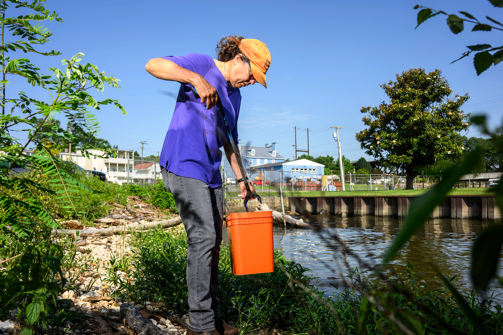 A photo shows Kim Clark using a grabber tool to put trash into portable plastic bin