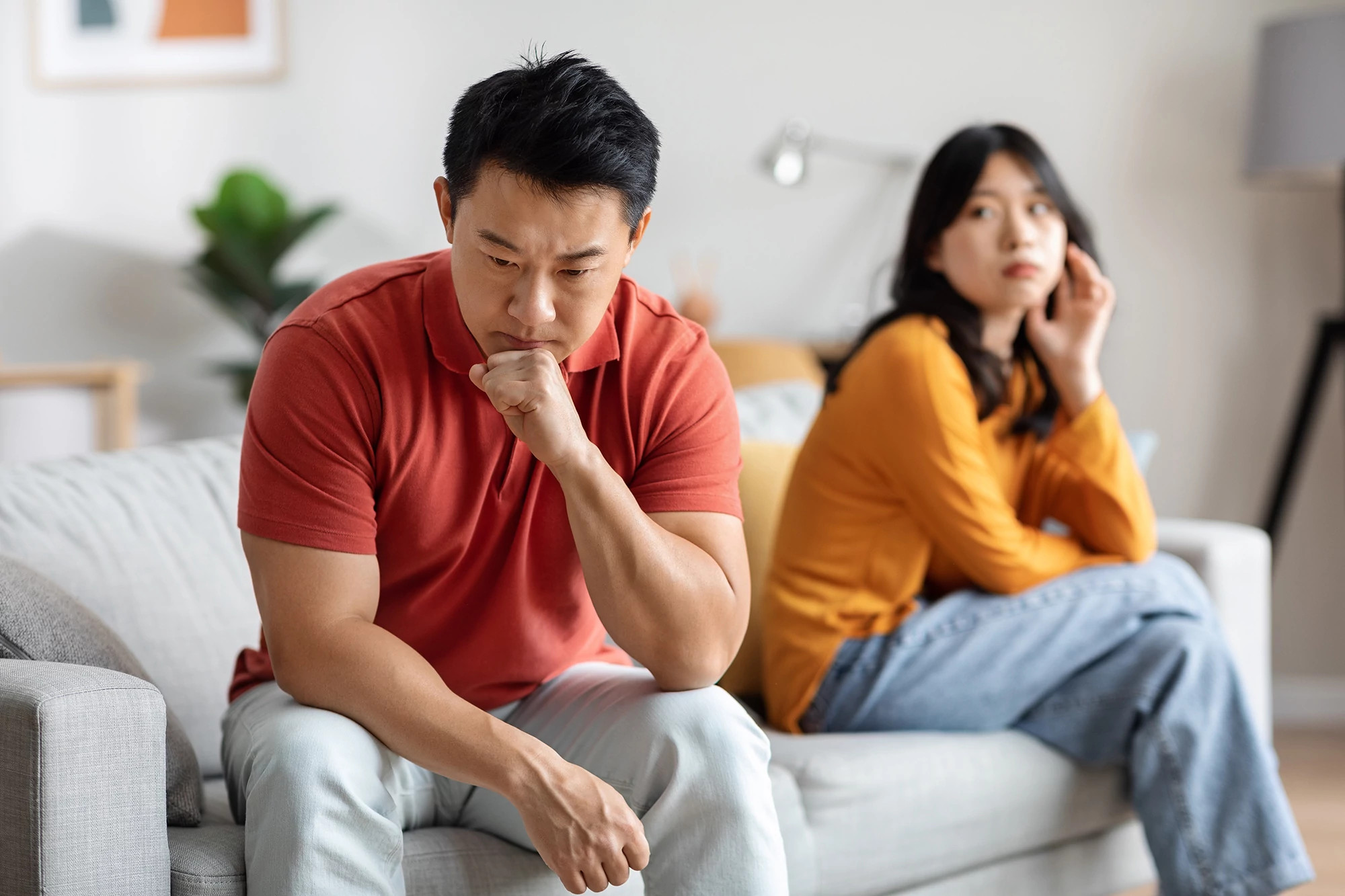 Asian couple fighting at home on the sofa