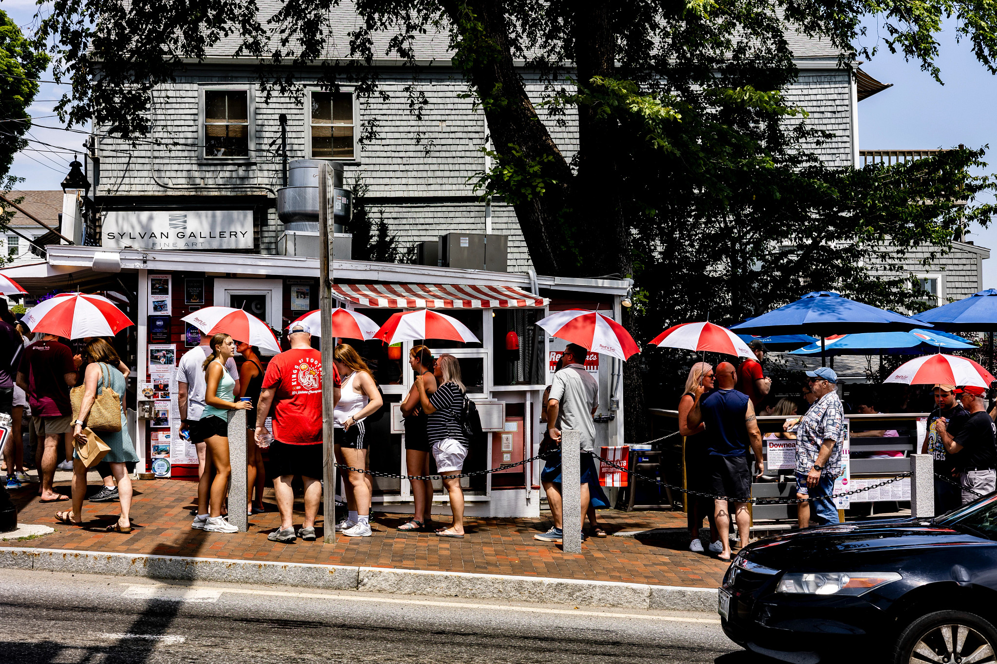 Customers hold umbrellas as they wait in line