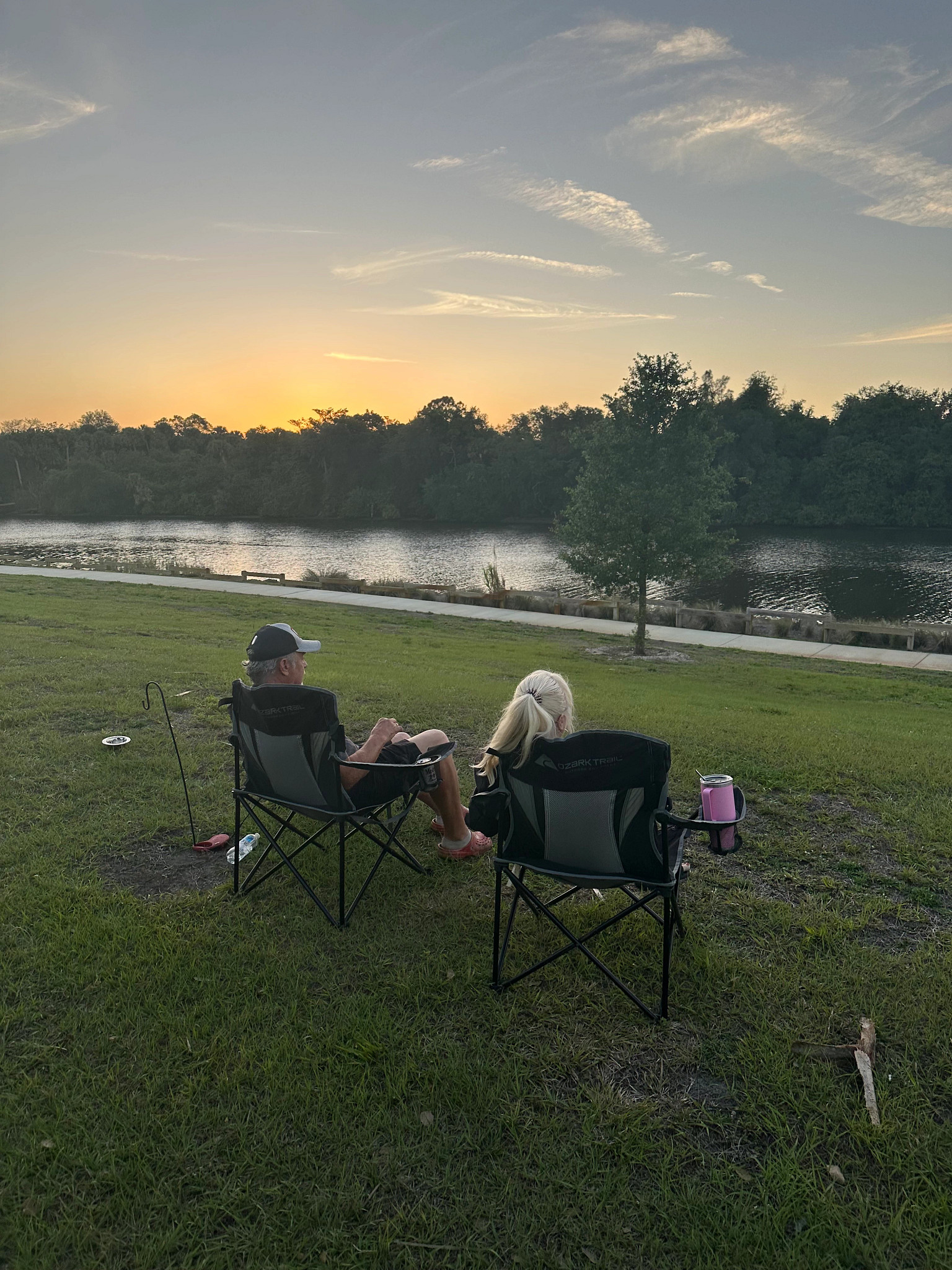 a couple sits on camping chairs, looking out at the water
